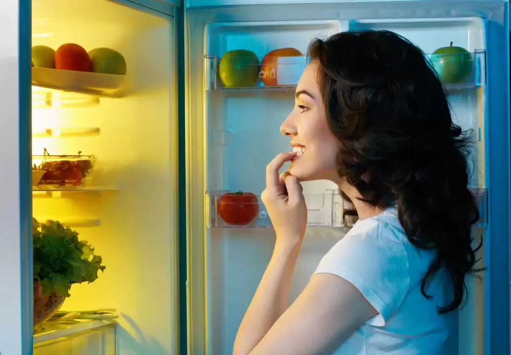 La fille regarde dans le réfrigérateur pendant la perte de poids rapide